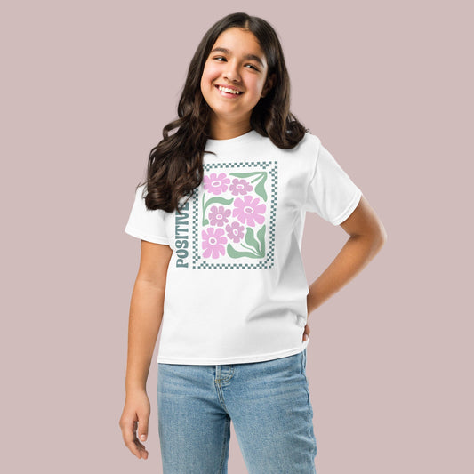 Girl wearing a white t-shirt with a floral design and the word 'Positive'.